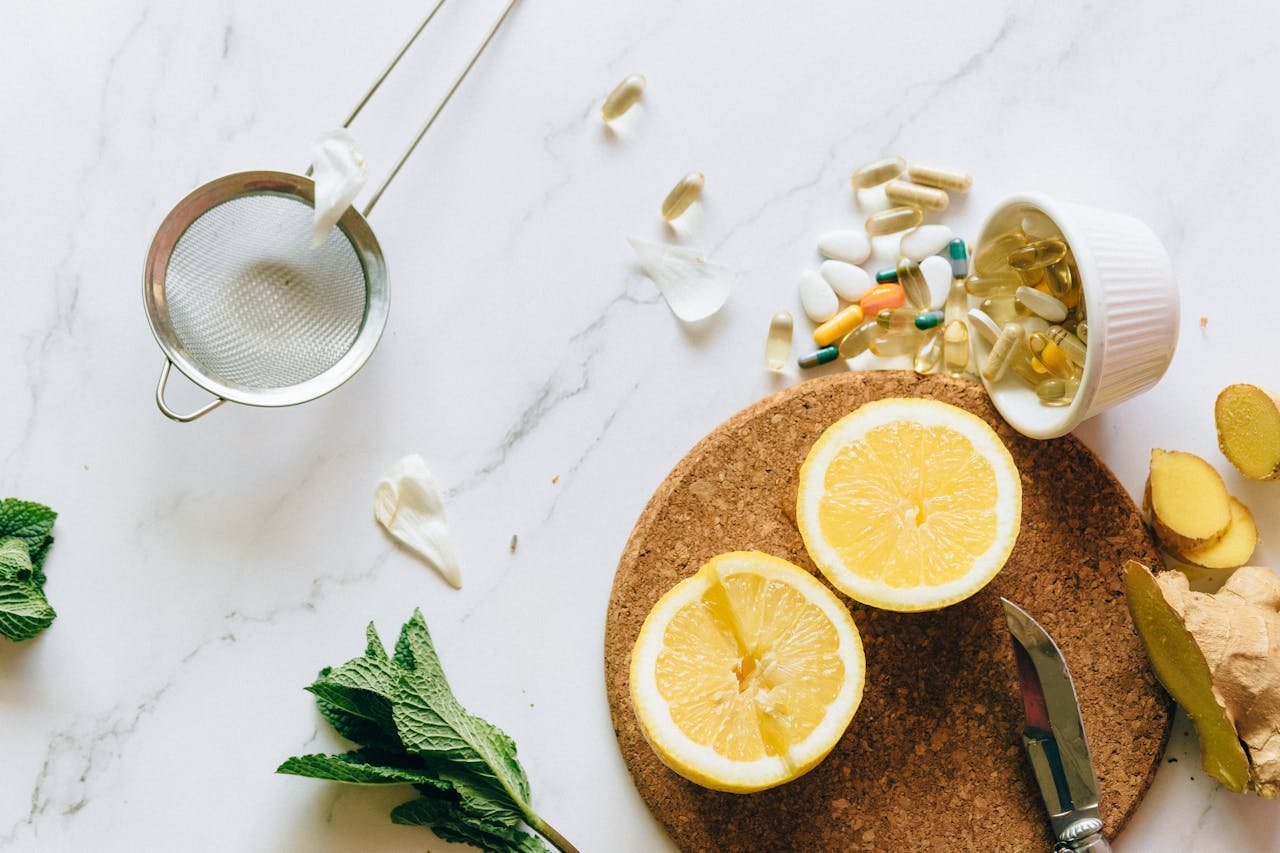 Flat lay of lemon, ginger, and supplements on a marble surface, illustrating natural remedies.
